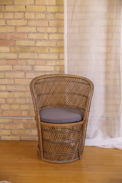 A dark rattan chair with a dark brown cushion.