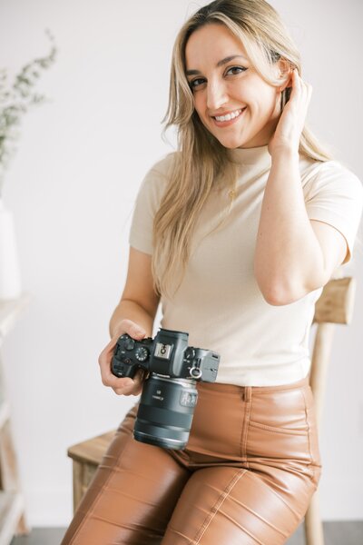 woman tucking in hair holding camera