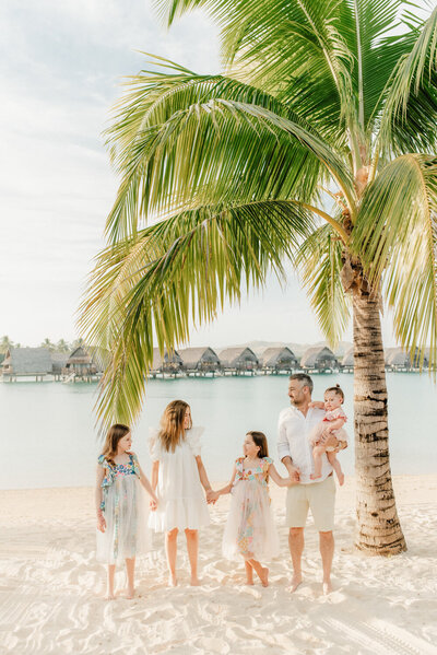 cute family under a palm tree on the beach