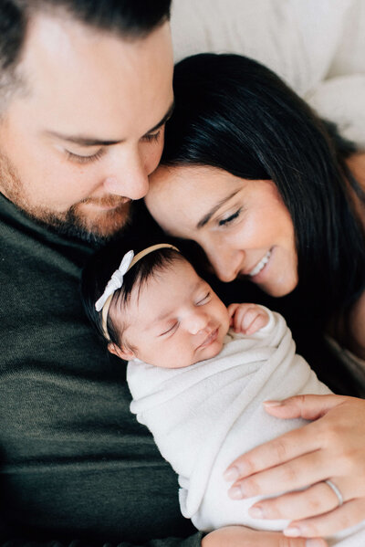mom holding baby girl facing outward and kissing her face