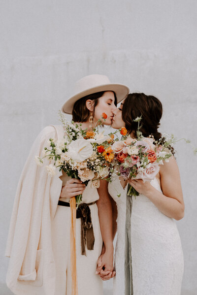 Brides kissing and holding their bouquets