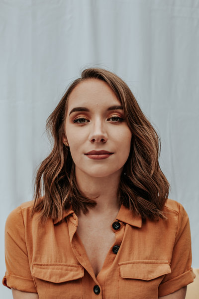 A self portrait taken infront of a white sheet, while wearing an orange dress