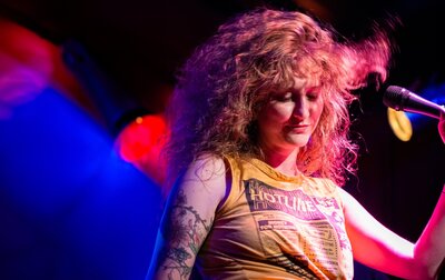 Allison dancing on stage with a microphone under multicolored stage lights in Austin, Texas.