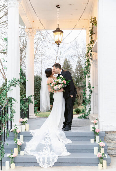 Bride and Groom kissing on front steps of Ceresville Mansion in Frederick, Maryland during a winter wedding. Taken by Bethany Aubre Photography.