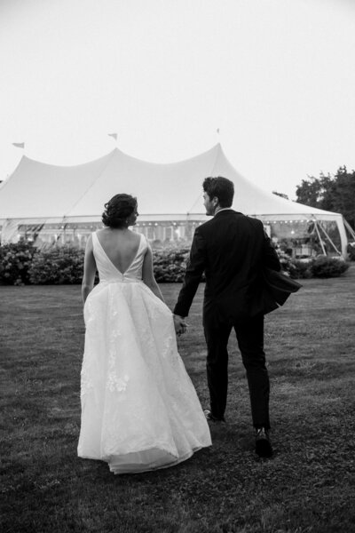 bride and groom walking towards tent