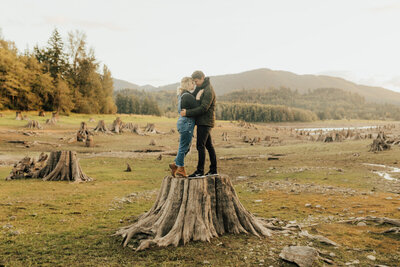 couple holding each other on a tree stump
