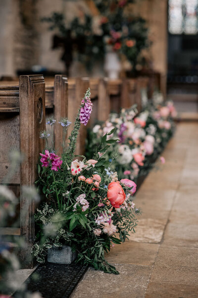 Two large white urns of flowers in front of the rood screen for this church wedding