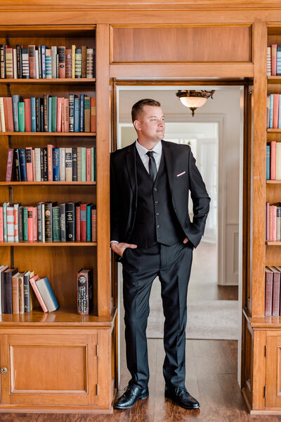 groom looking out window in library