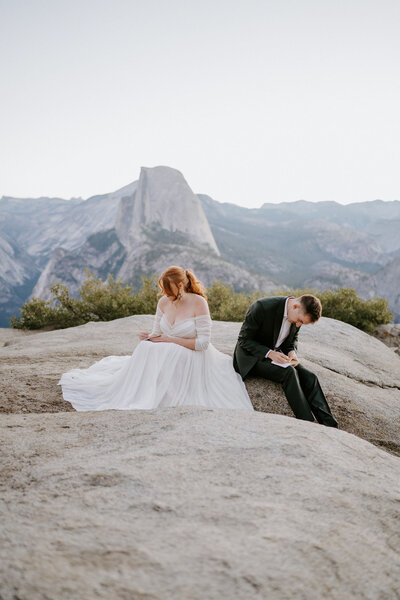 couple writing vows on elopement at glacier point at sunrise