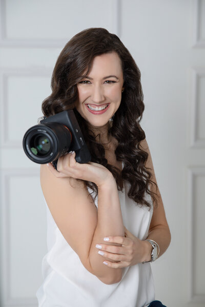 Massachusetts wedding  photographer meghan lynch holding a sony and smiling at the camera during a portrait session