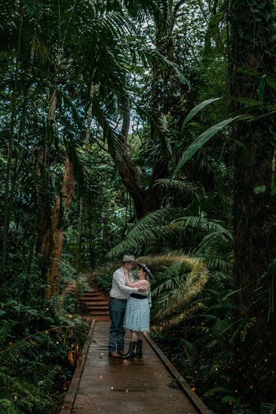 man and woman embracing on a bridge in the middle of a rainforest - Townsville Engagement Photography by Jamie Simmons