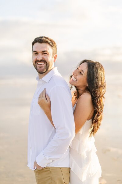 Engaged couple laughing on the beaches of Del Mar, California.