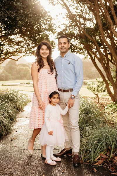 A family with a little girl holding hands as the sun sets behind them during a family photoshoot with auckland photographer michelle kelly