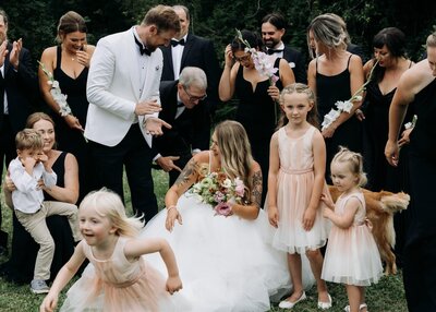 Two little girls in pink dresses hold flower purses and look excitedly towards the bride.