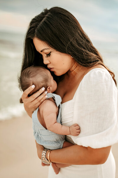 Family Photographer, a mother kisses her baby at the beach