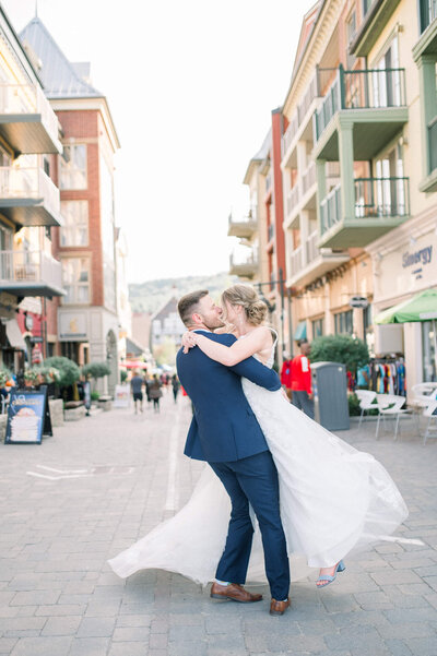 Groom lifts bride off her feet and spins her in the middle of the street.