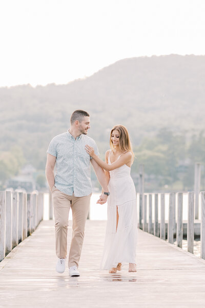 Portrait of an engaged couple holding hands as the groom kisses his bride's cheek. This light and airy engagement photo was taken at an abandoned golf course in Binghamton, NY