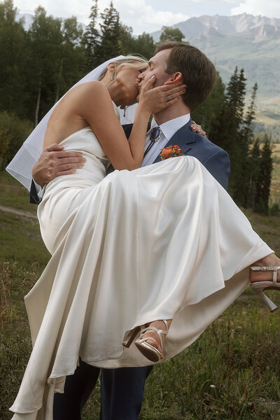 groom holding bride with mountain backdrop