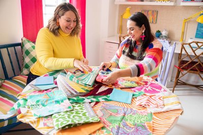 Two women look through colorful swatches and fabrics.