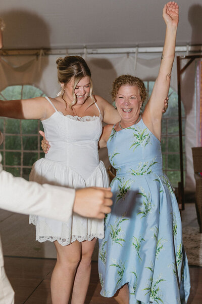 Bride dances with her mom excitedly at her wedding reception captured using flash photography