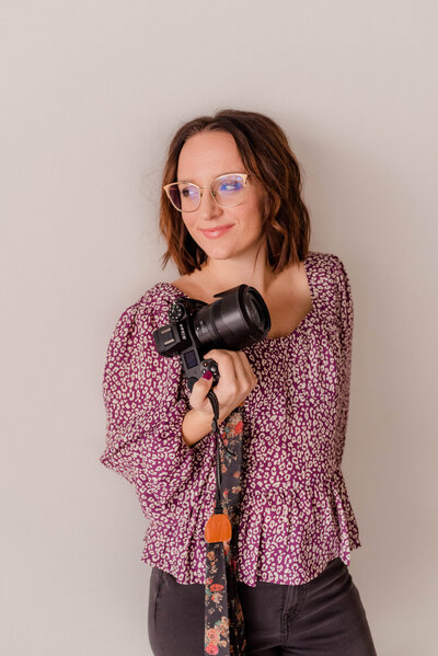 Woman poses for the camera with Nikon Z6II Camera in hand, smiling.