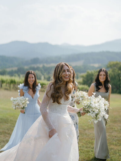Bride and bridesmaids holding white and green bouquets with lace ballgown and blue mismatched dresses
