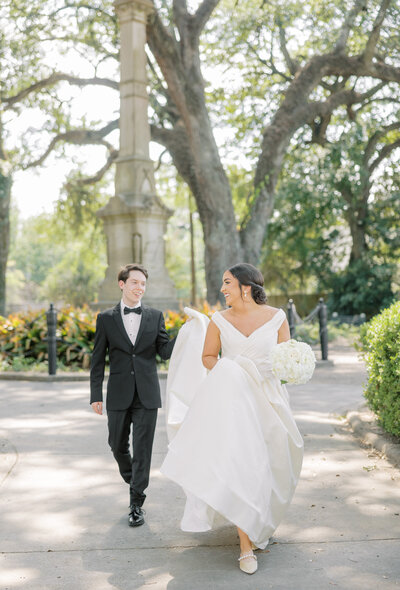 bride walking while groom holds her dress