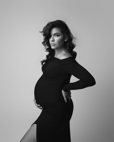 woman with sexy messy hair wearing black off-the-shoulder fitted maternity gown for a classic, editorial look.