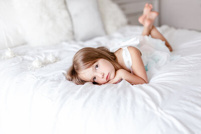 Whimsy image of 4 year old girl in a pretty dress  in a white bedroom