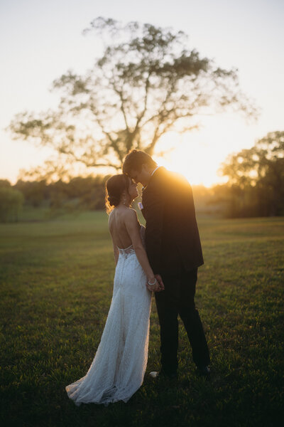 Couple touching foreheads as the sun sets behind them.