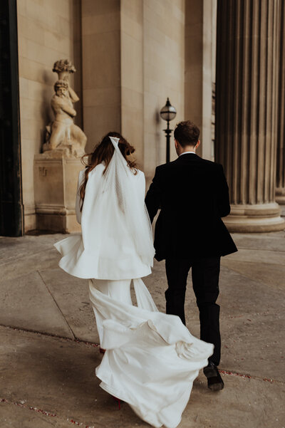 bride and groom walking away in the wind