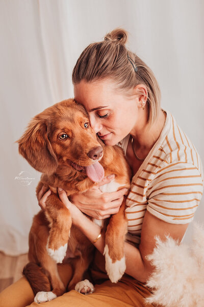 Dogmom knuffelend met haar tollerpuppy in de daglichtstudio te Geel.