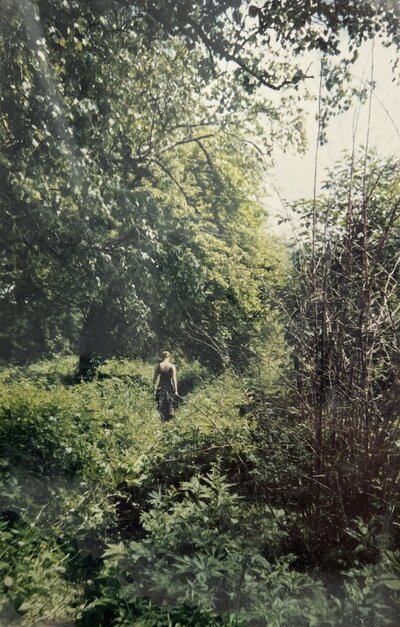 Becca Maniar walking through dense woods and brush