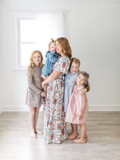 Mom and four daughters standing in light and airy studio space.
