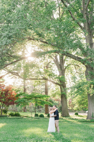 Engaged couple hug under a tree at Anchorage Trail in Louisville