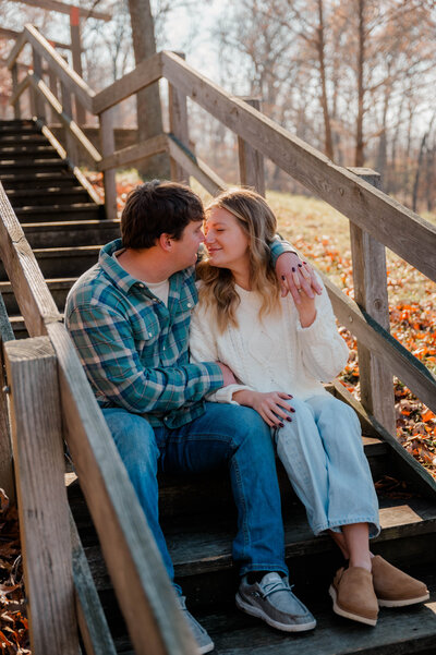 Couple sits on a stairwell, facing each other and touching noses.