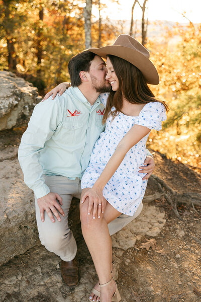 Man kissing woman wearing cowboy hat during warm, outdoor Nashville engagement session