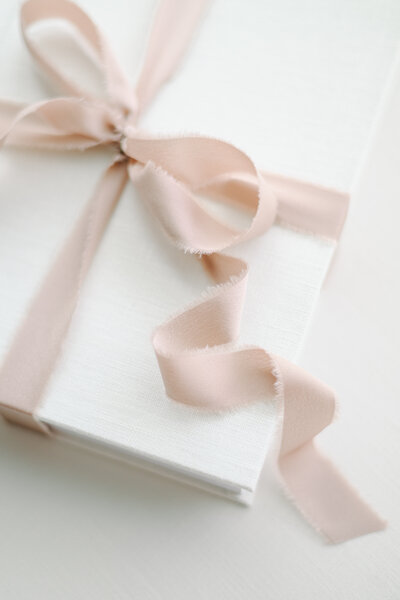 white wedding album with pink ribbon