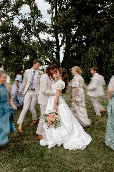 a bride and groom with their bridal party running around them