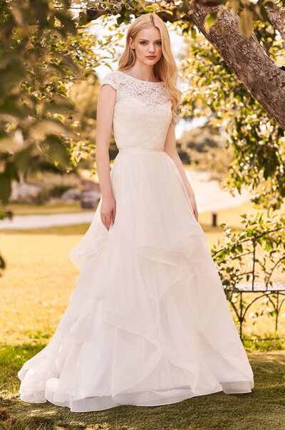 Crêpe, Mesh Tulle, and Mikaella Lace Wedding Dress. Cropped lace top with bateau neckline, cap sleeves, and fabric covered buttons down back. Sweetheart neckline on lining. High waist multi-layered Mesh Tulle skirt with Crêpe waistband and 2″ horsehair edging on hems.