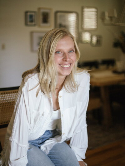 Interior designer Kaitlyn Schultz relaxing in a cozy, sunlit living space featuring layered textures and warm tones.