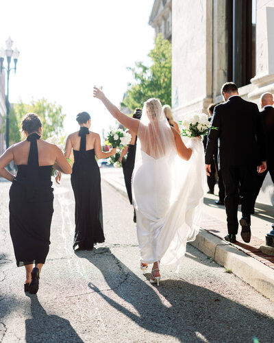 Bride walks hand in hand with her veil flowing behind her at an outdoor Pittsburgh wedding in natural light