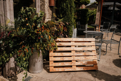 Order of the day on a palette outside Cripps Barn with Orange flowers in a milk churn for a rustic wedding