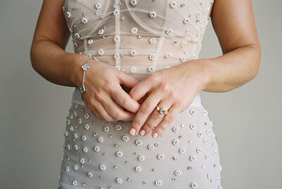 Bride in beaded flower gown shows off engagement ring