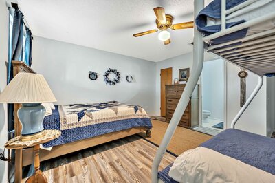 Bedroom with bunk beds and queen bed in with half bath at this 3-bedroom, 2.5 bathroom rural vacation rental house just minutes outside of downtown Waco, TX.
