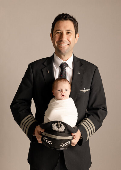 Dad wearing pilot uniform during newborn session in studio by Ashley Nicole Photography