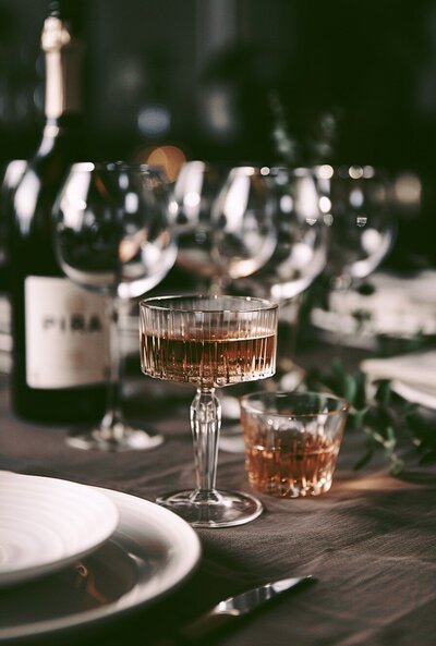 place setting with wine glasses and  champagne glass with pink champagne in it