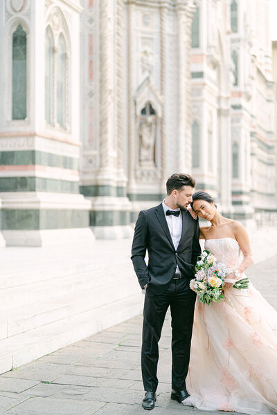 Bride wears tulle two-tone dress holding grooms hand while wedding officiant speaks during ceremony