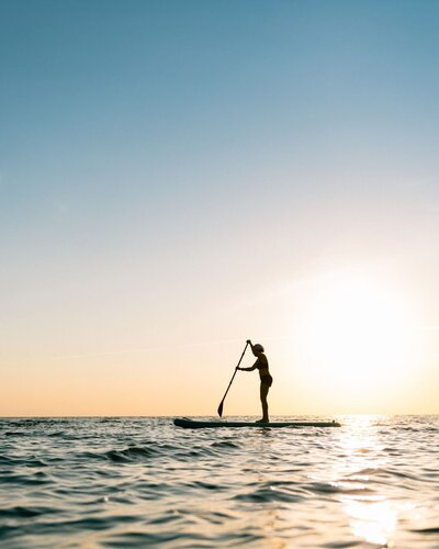 WOMAN ON PADDLEBOARD IN SEA