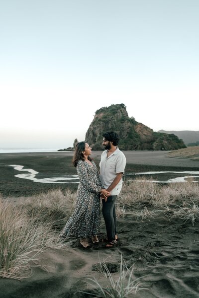 Engaged couple Keerthana and Suraj walking along sandy beach path in Auckland during engagement session, photographed by Zanthe Vorsatz.